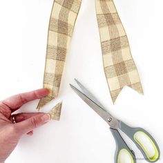 someone is cutting fabric with scissors on a white surface and another pair of scissors next to it