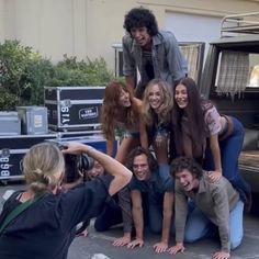 a group of young people posing for a photo in front of a truck with their legs spread out