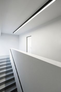 an empty room with stairs leading up to the second floor and light coming from above