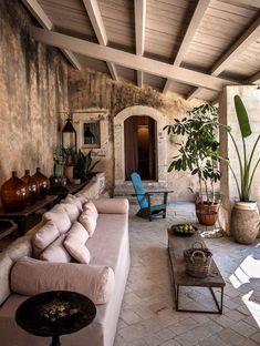 an outdoor living area with couches, tables and potted plants