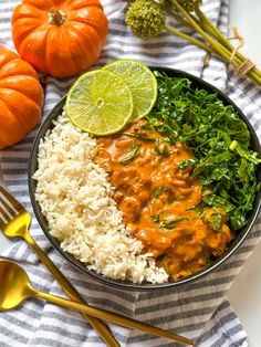 a bowl filled with rice and vegetables next to two orange pumpkins on the side