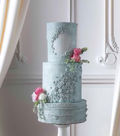 a three - tiered blue cake with pink flowers on top