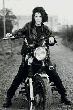 a man riding on the back of a motorcycle down a dirt road