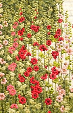 a quilted wall hanging with red and pink flowers