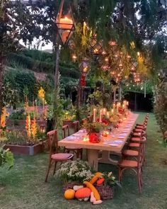 an outdoor dining table with lots of vegetables and candles in the center is surrounded by greenery