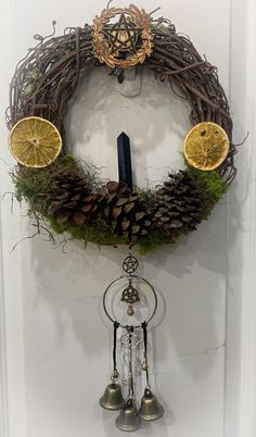 a wreath with pine cones, orange slices and bells hanging on the wall next to a door