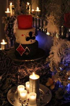 a table topped with candles next to a cake covered in cards and playing cards on it