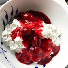 a bowl filled with cream and cherries on top of a blue and white plate