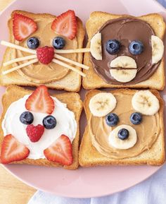 four slices of toast with peanut butter, bananas and strawberries on them in the shape of cats