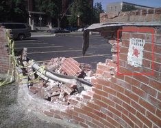 a fire hydrant that is sitting in the middle of a brick wall with a hose attached to it