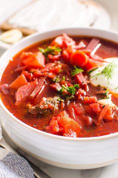 a white bowl filled with meat and tomato soup