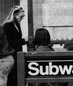 a group of people standing around a subway sign