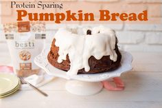 a pumpkin bread with icing sitting on top of a cake plate