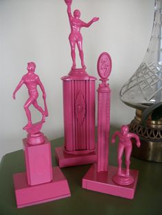 three pink figurines are sitting on top of a green table next to a clock