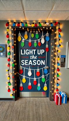 an open door decorated with christmas lights and presents on the floor next to it is a sign that says light up the season