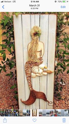 a wooden sign with a mermaid sitting on it's back and holding a piece of food