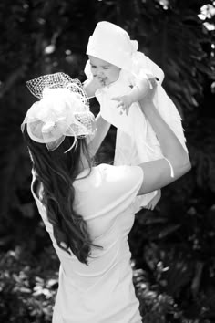 a woman holding a baby in her arms and wearing a hat on top of her head