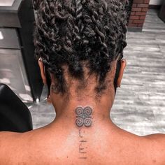 the back of a woman's neck with a tattoo on her left shoulder and two spirals in the middle