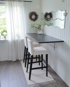 a table with four stools in front of it and two mirrors on the wall