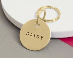 a gold keychain with the word daisy on it sitting next to a white plate