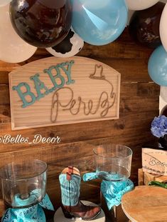 there is a baby shower sign on the wall next to some cups and balloons in front of it