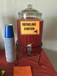 a red table topped with a blue and white cup next to a metal container filled with liquid