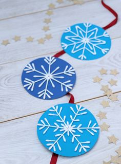 paper snowflakes are hanging from red ribbon