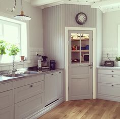 a kitchen with wooden floors and white walls, has a clock on the wall above the sink