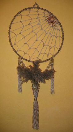 a decorative item hanging on the wall with chains and feathers attached to it's sides