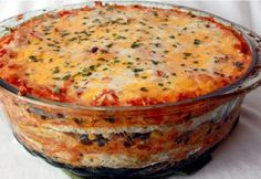 a casserole dish with cheese and vegetables in it on a white tablecloth