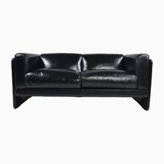 a black leather couch sitting on top of a white floor next to a wooden frame