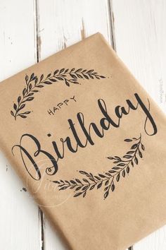 a brown paper bag with the words happy birthday written on it and an olive wreath