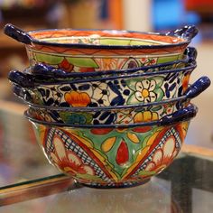 four colorful bowls are stacked on top of each other in the middle of a glass table