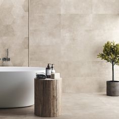 a white bath tub sitting next to a wooden table and potted plant on top of it