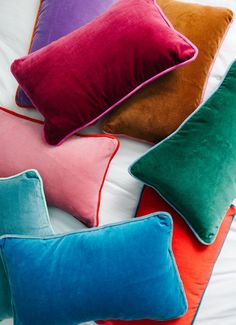 four different colored pillows on top of a bed