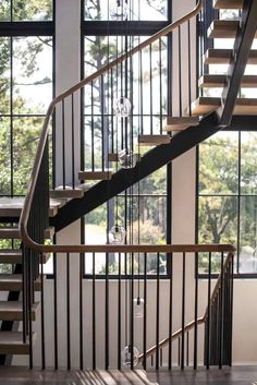 a spiral staircase with glass balconies and metal handrails in front of large windows