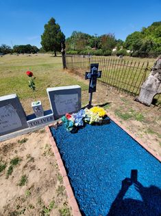 a cemetery with flowers and headstones on the ground in front of a fenced in area