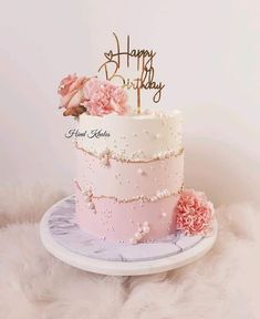 a pink and white birthday cake with flowers on top