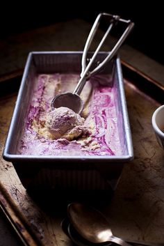 a bowl filled with ice cream next to two spoons