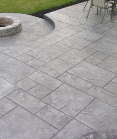 an outdoor patio with concrete pavers and fire pit in the center, surrounded by grass