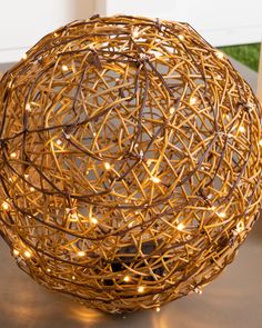 a decorative ball made out of branches with lights on the top and bottom, sitting on a table