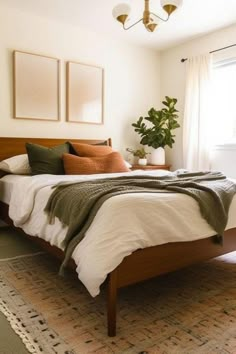 a bed sitting in a bedroom next to a window with two plants on top of it