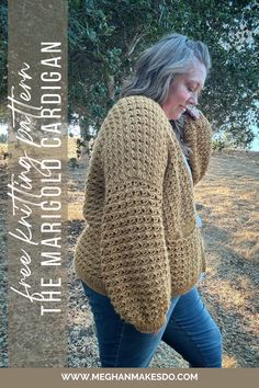 a woman is walking in the woods with her hand on her ear and wearing a crocheted sweater