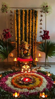 an arrangement of flowers and candles in front of a statue