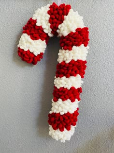 a red and white knitted candy cane ornament hanging from a hook on a wall