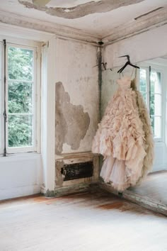 a dress hanging on a clothes rack in an old room with paint peeling off the walls