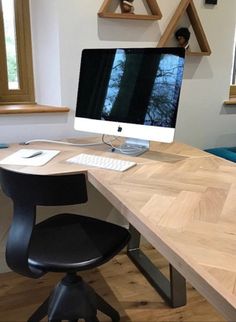 an apple computer sitting on top of a wooden desk next to a blue chair and window