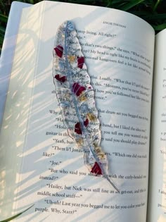 an open book with a feather brooch attached to it's cover, sitting in the grass