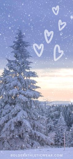 a snow covered pine tree with hearts drawn on it's branches in the foreground