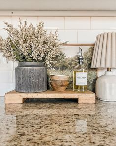 a table topped with vases filled with flowers next to a lamp on top of a counter